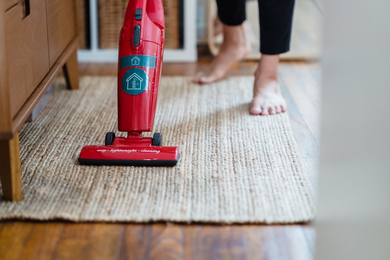 contact-img A red vacuum cleaner on a carpet in a stylish home setting with barefoot user.